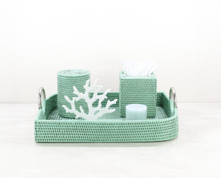 ECO HANDCRAFT sage green leaf-shaped rattan tray styled on a bathroom counter with tissue box, candle, and coral decor.