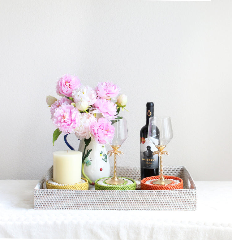 Anniversary gift set styled with handwoven whitewash rattan tray, seashell coasters, hand-painted stoneware picture, and floral pitcher with pink flowers