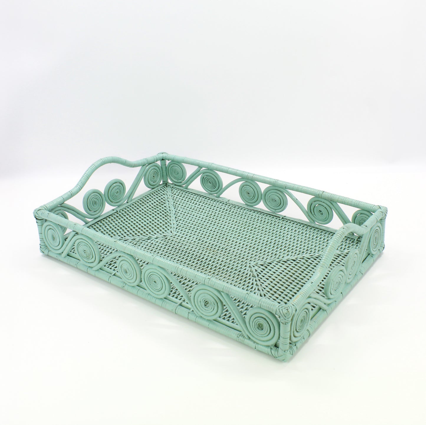 Empty sage leaf green rectangle rattan tray with swirl design and raised handles, handmade for serving or home décor.