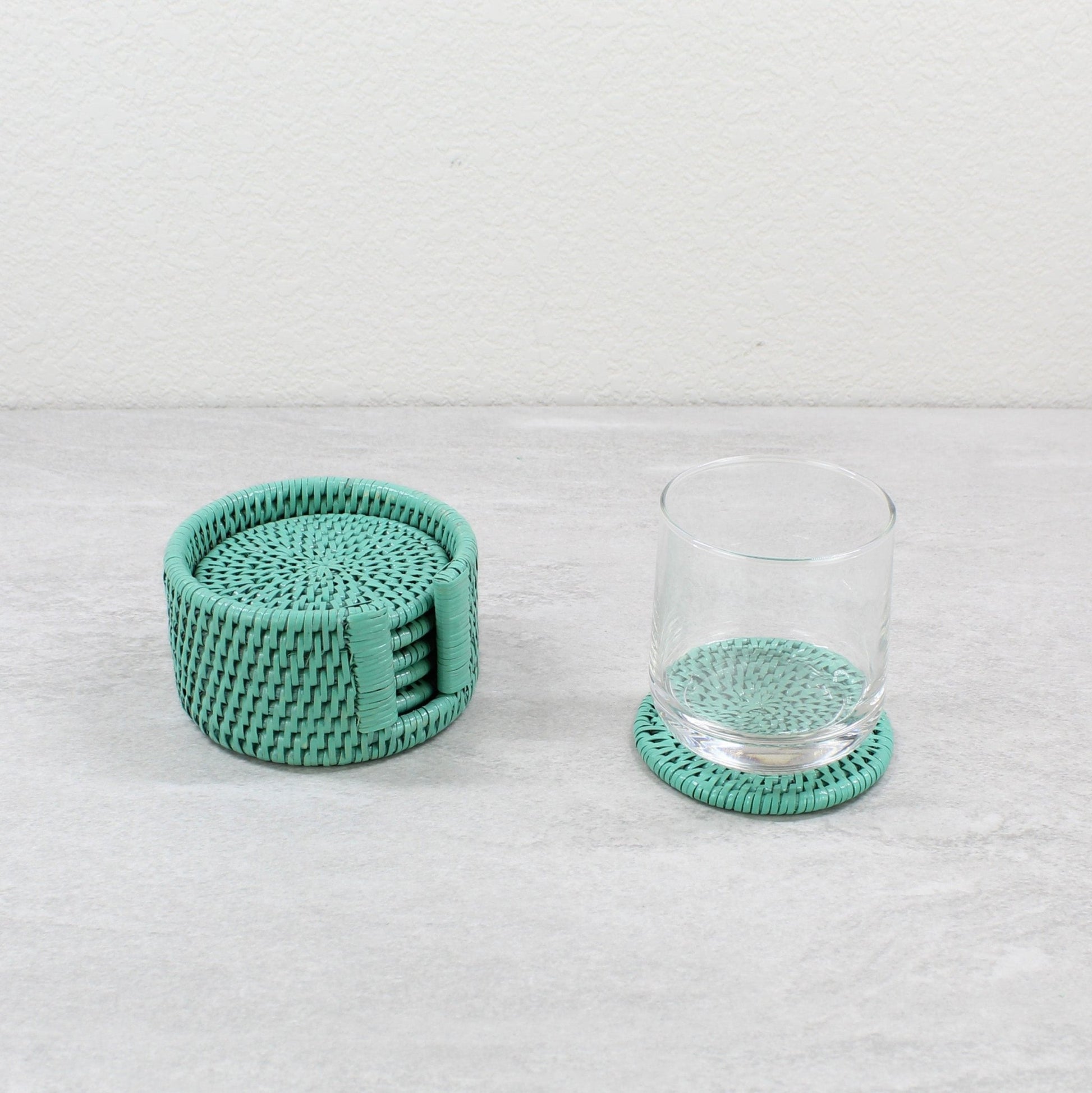 Set of turquoise round rattan coasters with glass cup, ideal for protecting surfaces with style