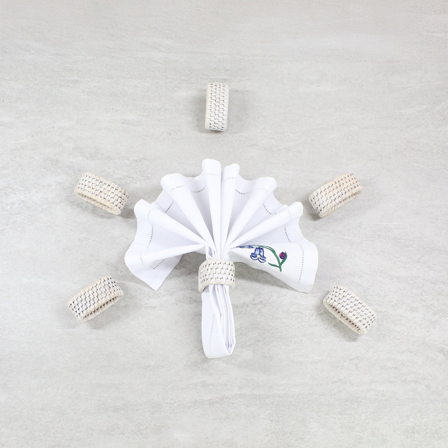 ECO HANDCRAFT whitewashed rattan napkin rings set of 6, styled with a folded cloth napkin for elegant dining décor