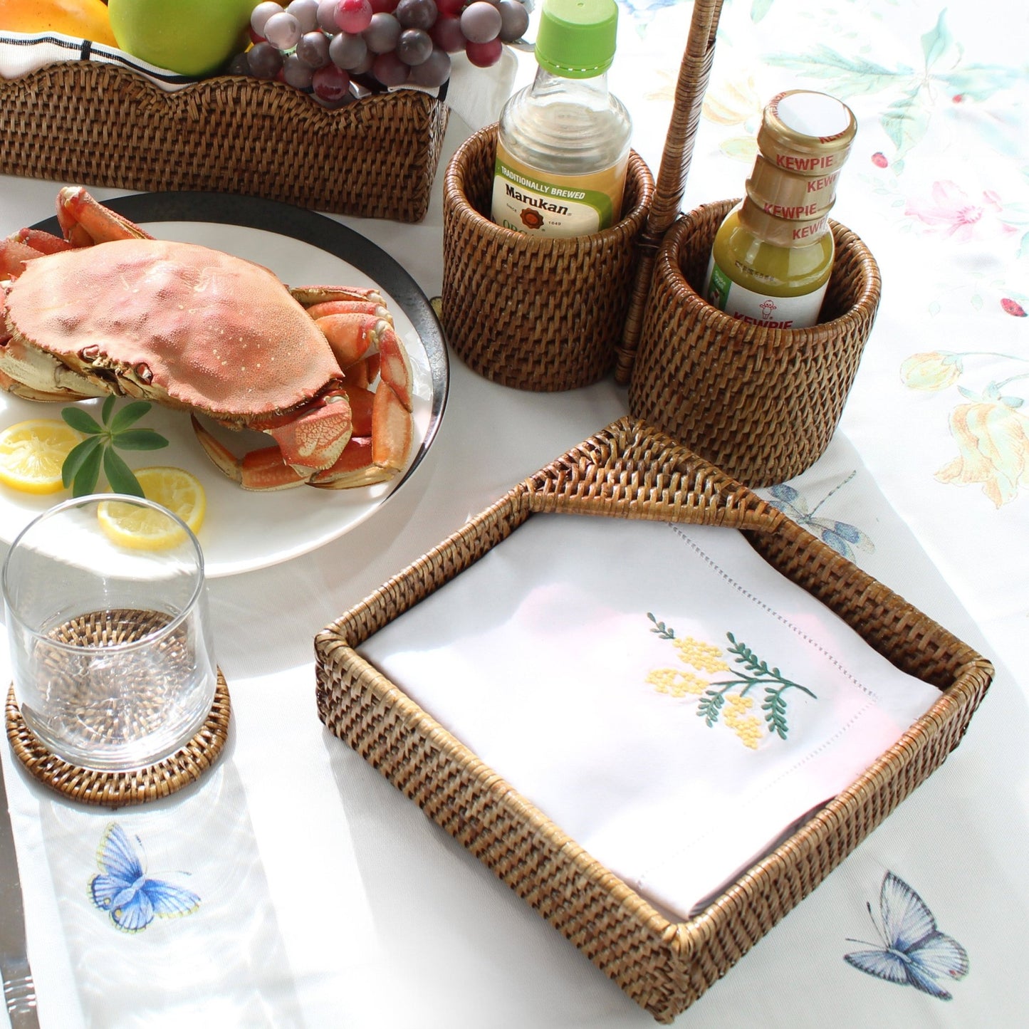 ECO HANDCRAFT rattan napkin and sauce bottle holders on a tropical table setting with fresh crab and drinks