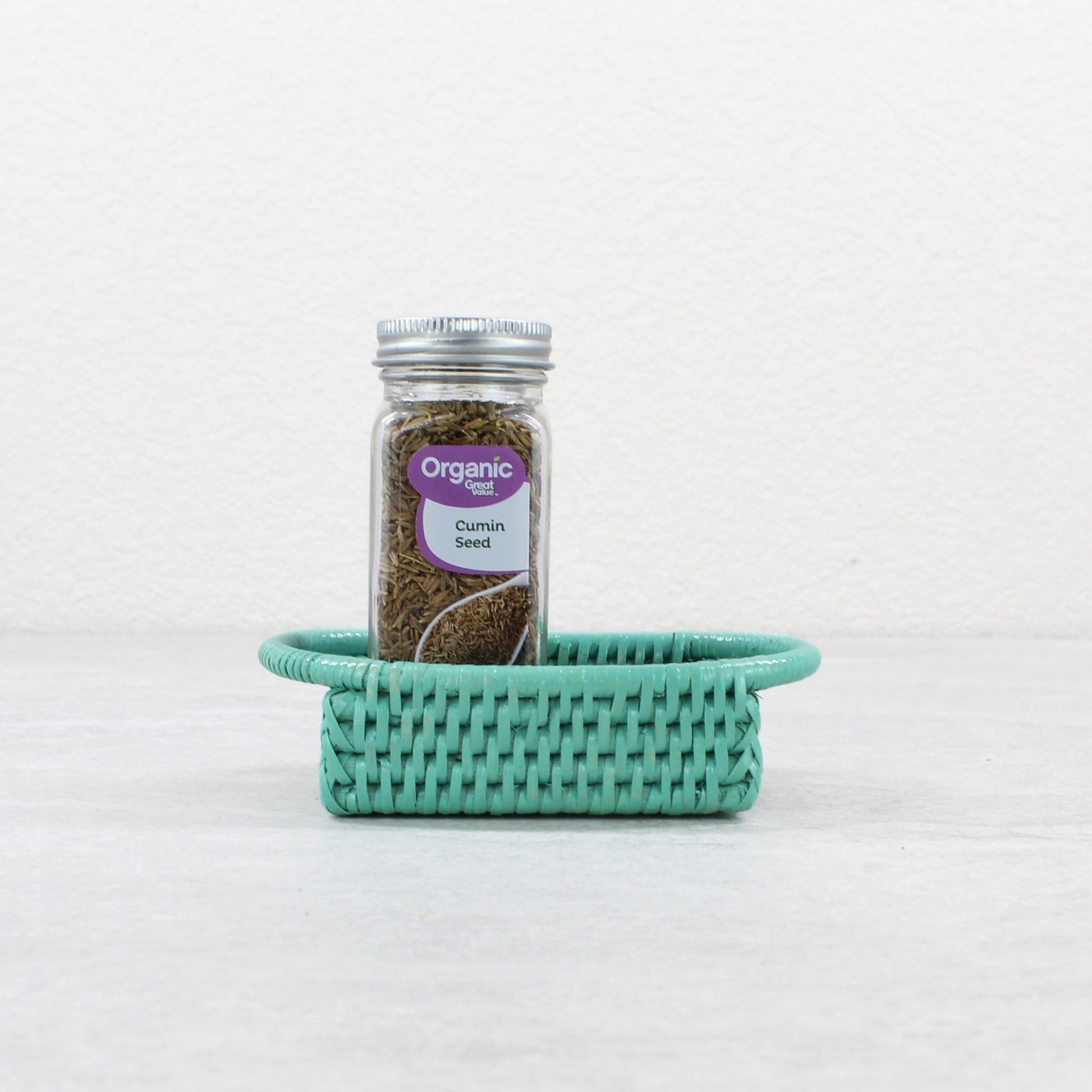 Handmade ECO HANDCRAFT turquoise rattan tray holding organic cumin, perfect for spice storage or tabletop use.