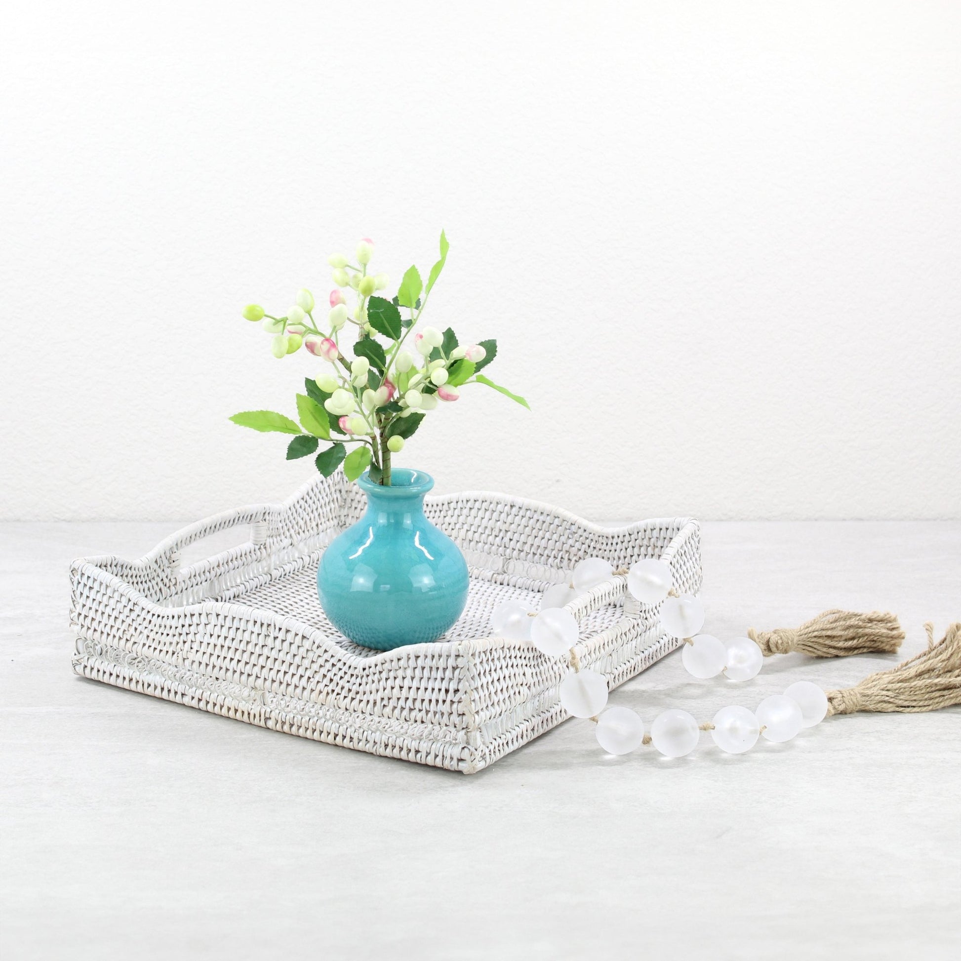 ECO HANDCRAFT whitewashed scalloped rattan tray styled with a blue vase and beads for serene, coastal home décor