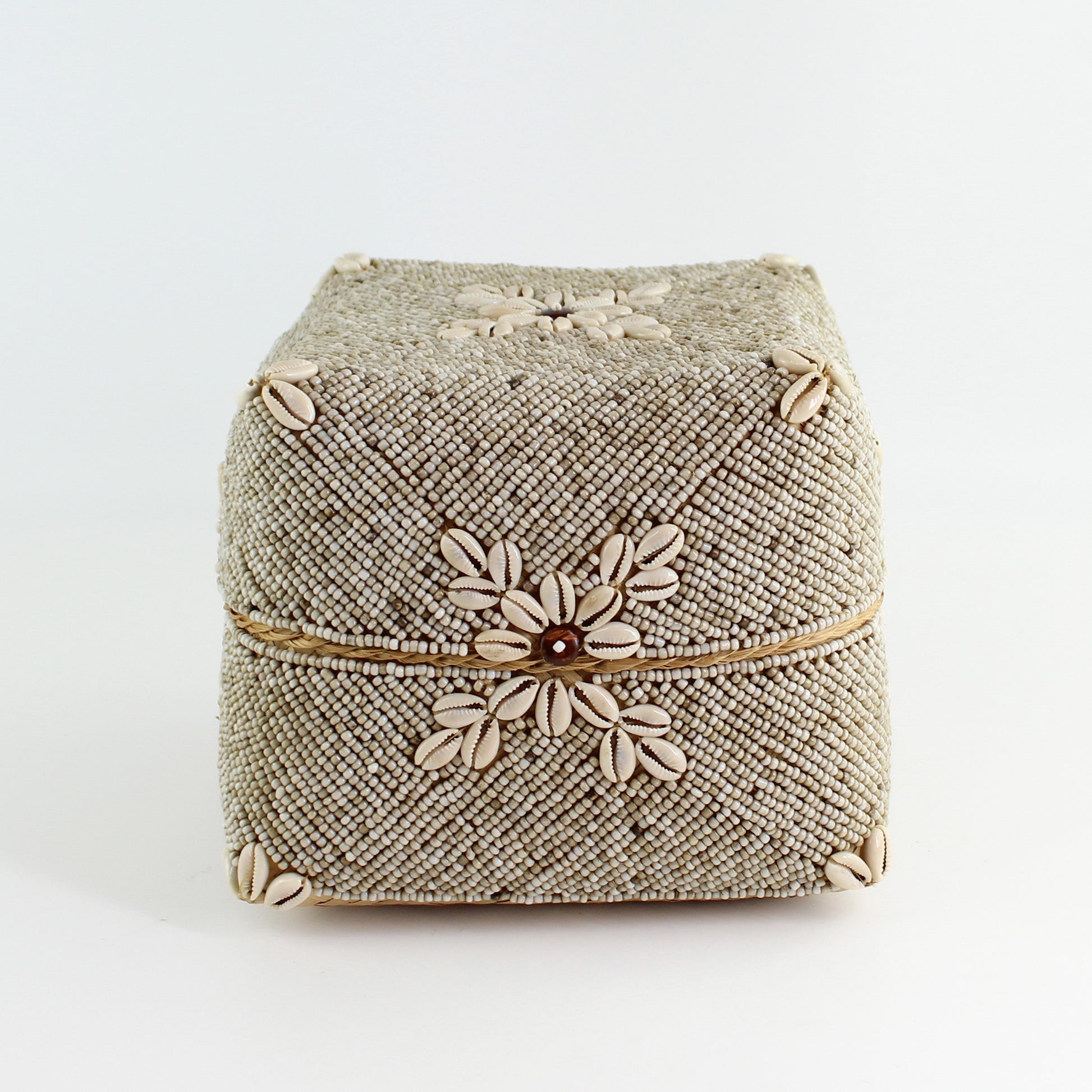 Close-up of large handmade beige beaded cowrie shell storage box highlighting shell flower details and fine woven beadwork.