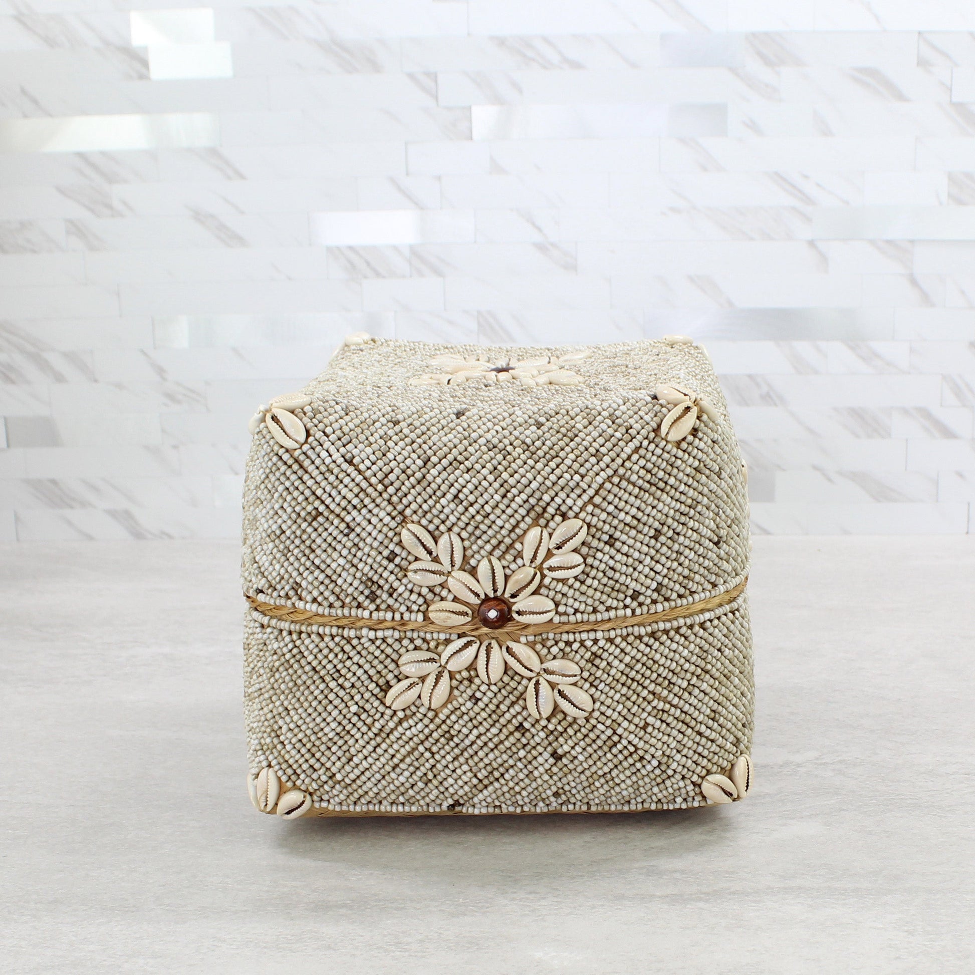Large beige beaded storage box decorated with natural cowrie shells and central flower motif in coastal boho décor style.