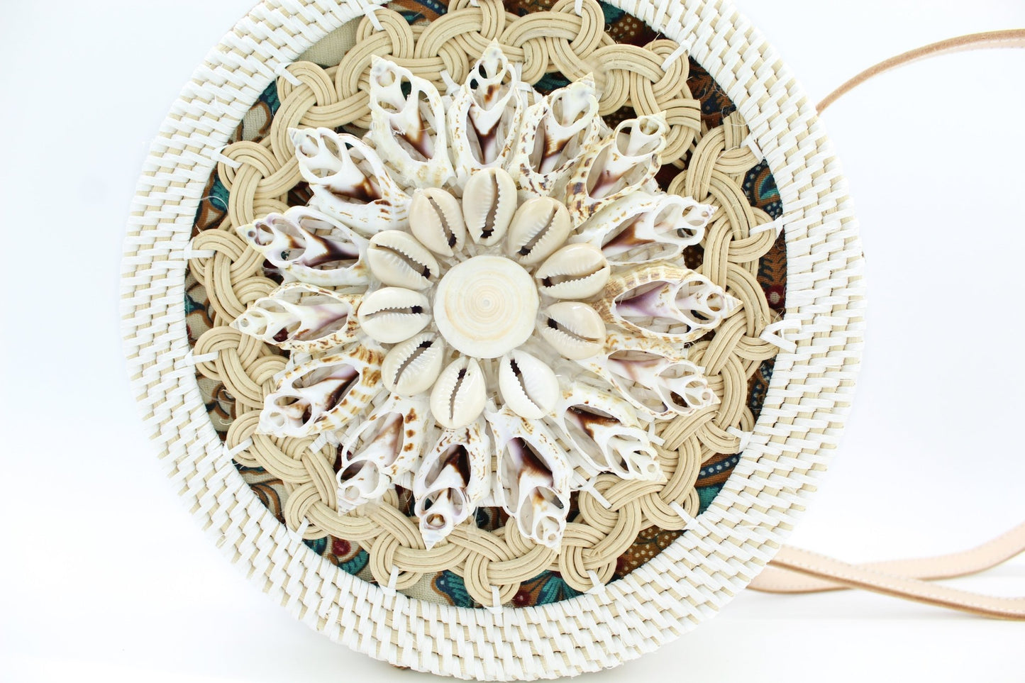 Close-up of handcrafted seashell flower pattern on woven rattan bag, highlighting artisan texture and tropical detail.