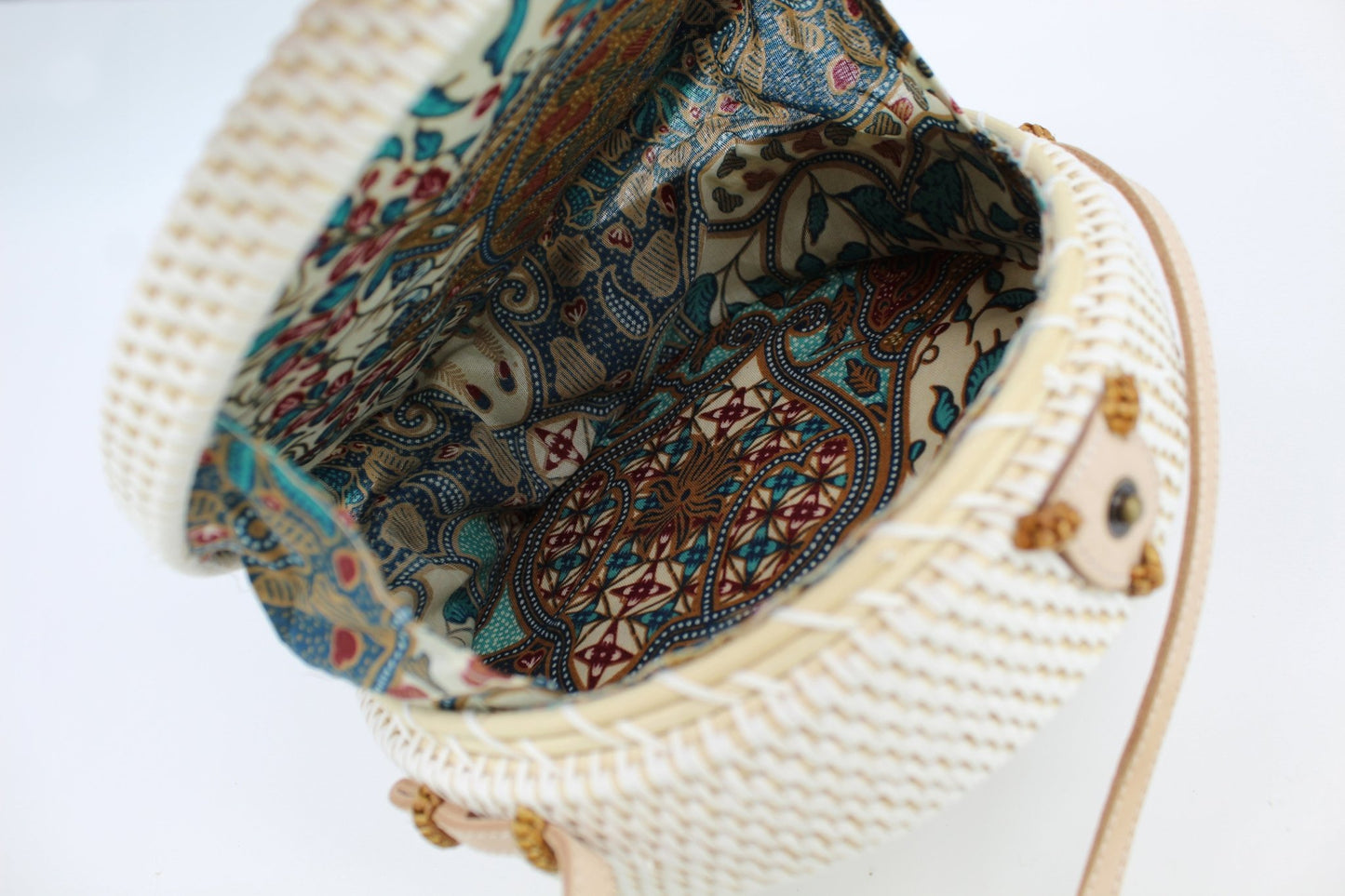 Interior of round rattan crossbody bag with fabric lining and magnetic closure, compact yet stylishly