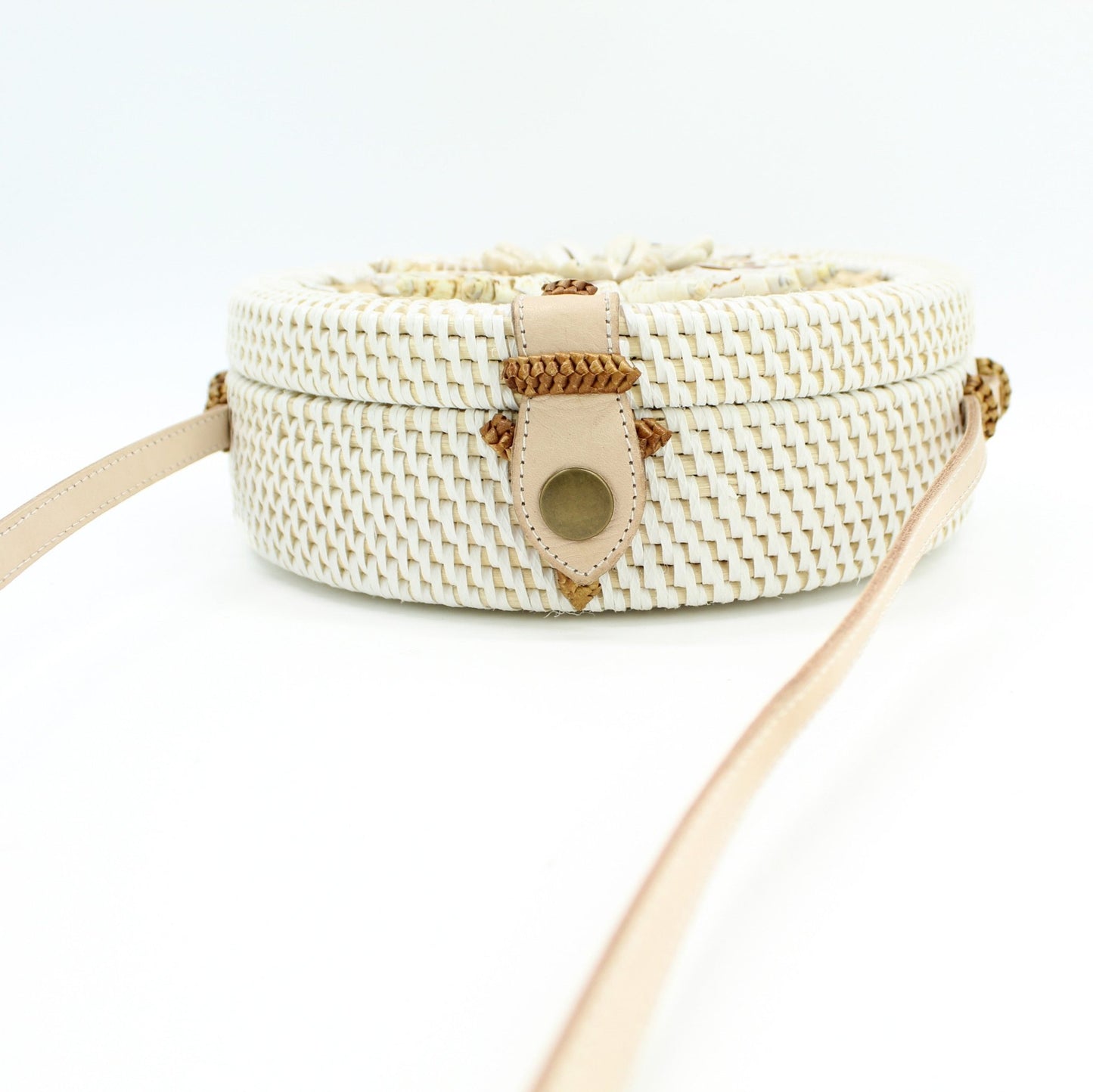 Side view of Bali rattan crossbody bag with leather strap and seashell accents, showing slim round
