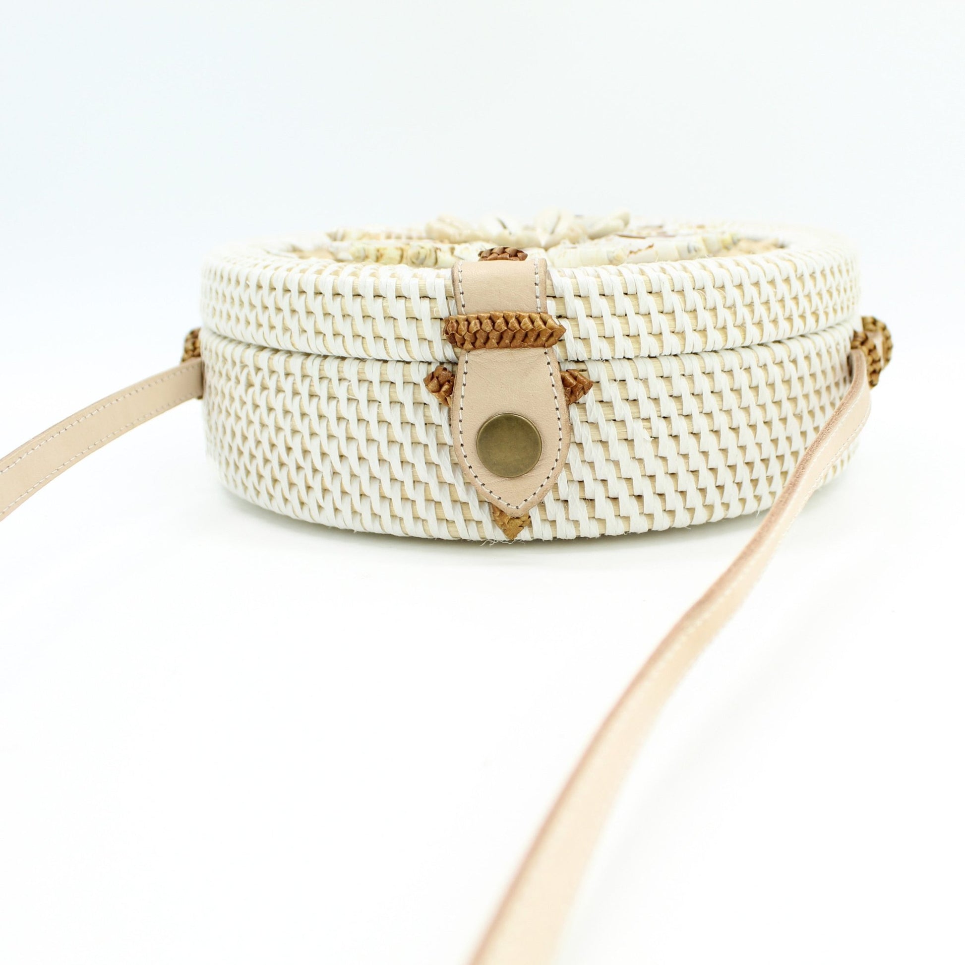 Side view of Bali rattan crossbody bag with leather strap and seashell accents, showing slim round