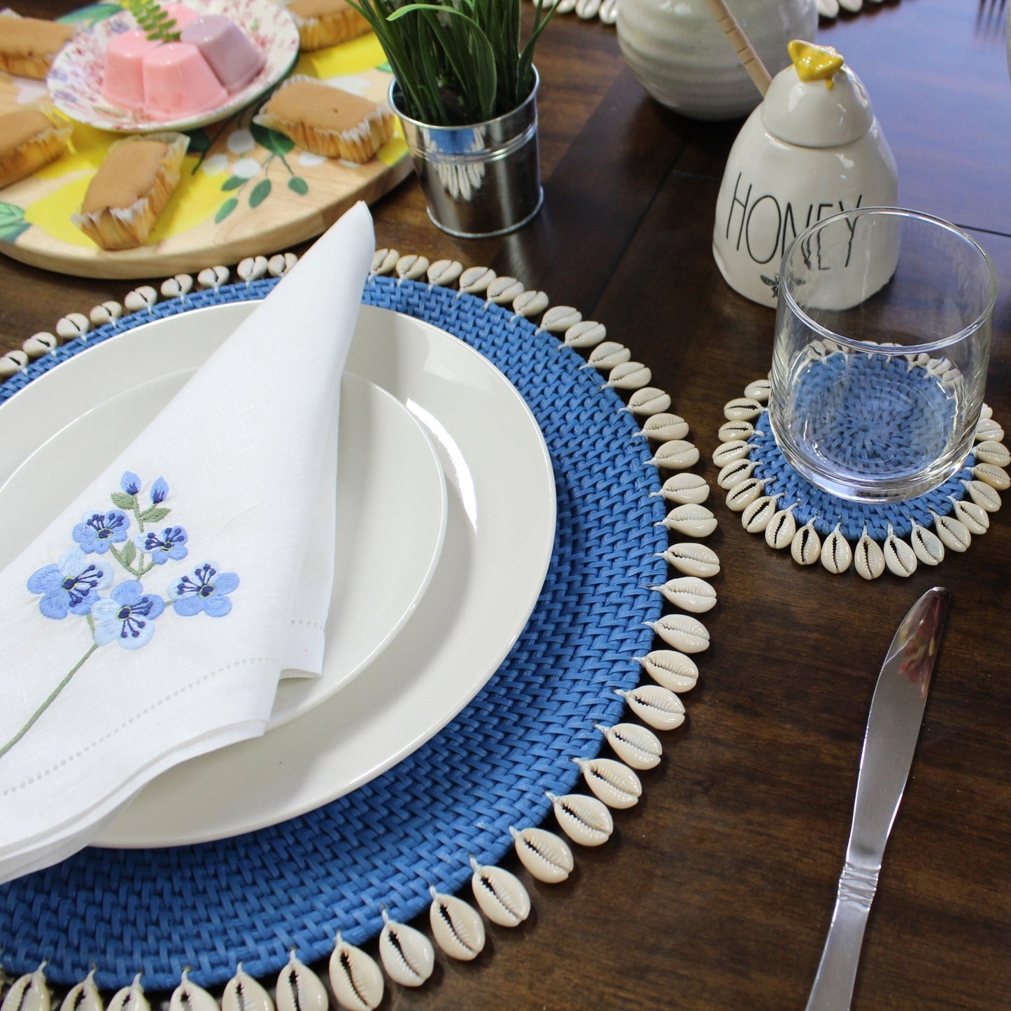 Blue eco-friendly rattan coasters styled in coastal home with candles, flowers, and tropical table décor