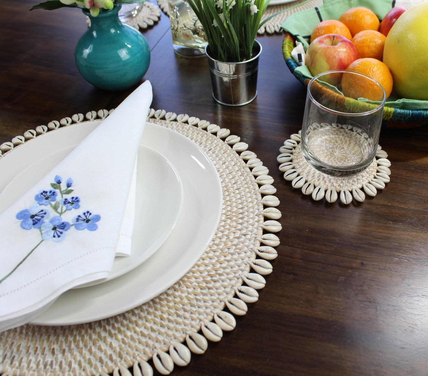 Whitewash eco-friendly rattan coasters styled in coastal home with candles, flowers, and tropical table décor