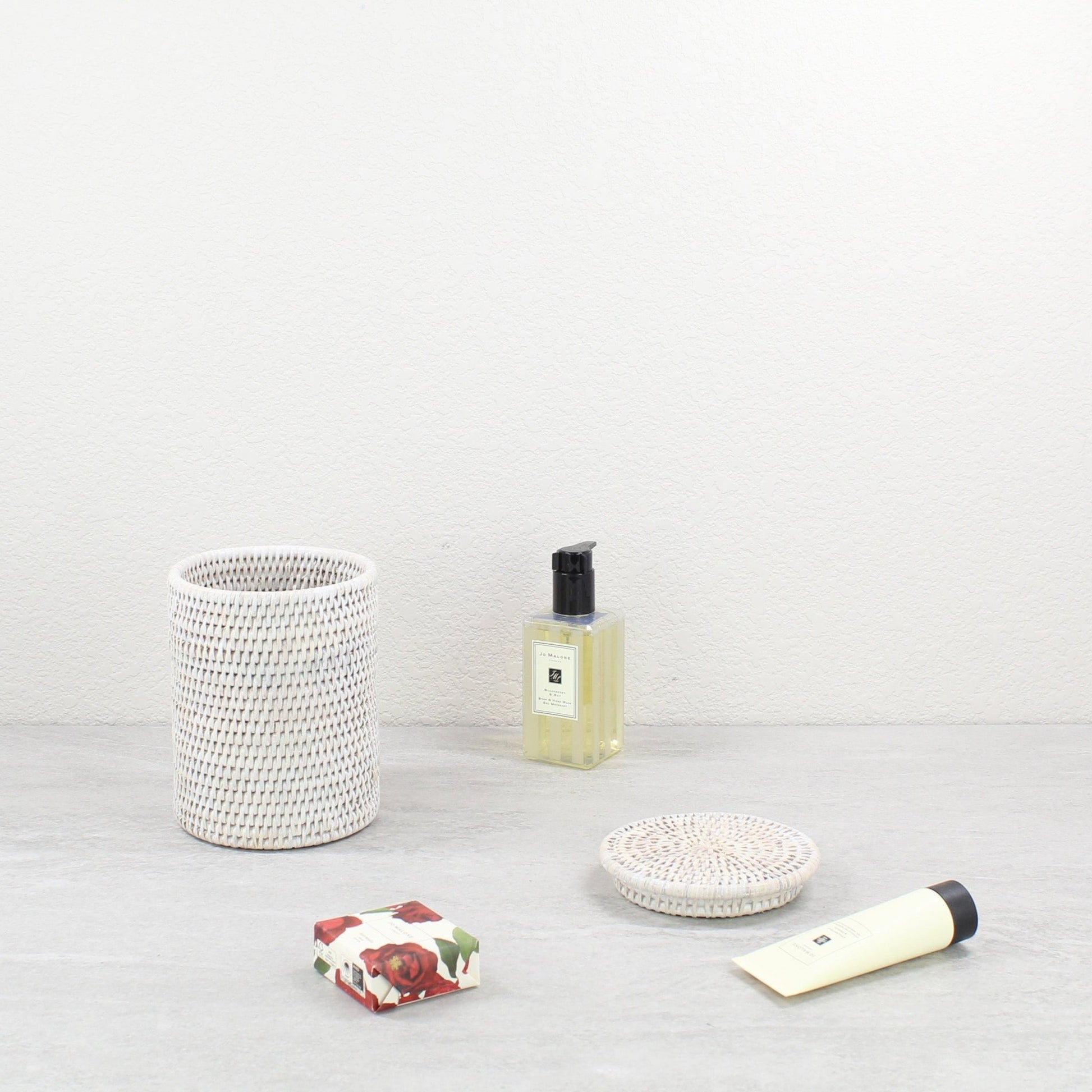 Eco Handcraft whitewash rattan canister and lid with luxury spa items, styled for elegant bathroom countertop decor