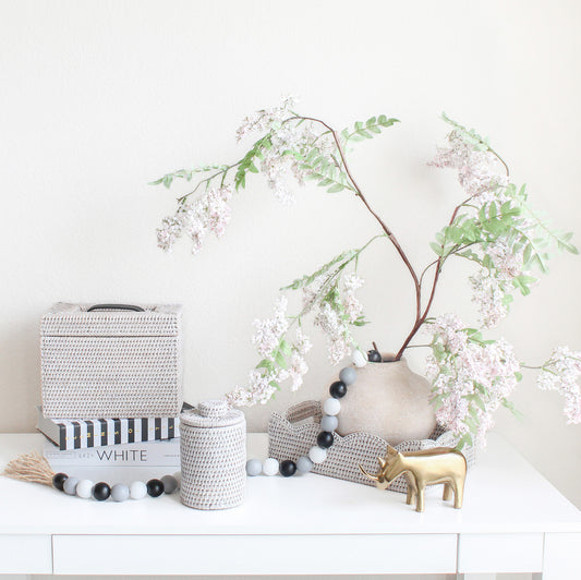 Handwoven whitewash rattan storage set styled with flowers, gold accent, and books for elegant home décor