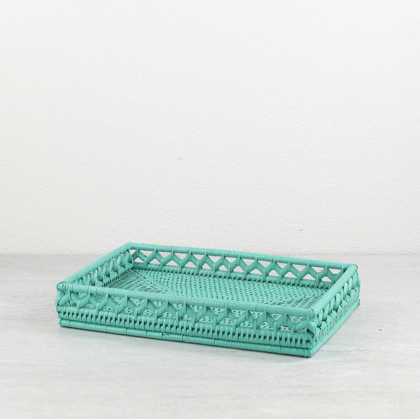 Turquoise handwoven rectangular rattan tray with intricate cutout design for elegant coastal home décor or bathroom vanity