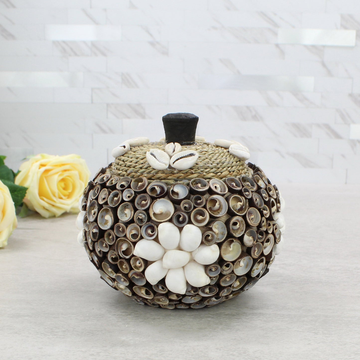 Large cowrie seashell storage box with rope lid, artisan handmade, styled with floral décor for coastal home or cottage display.