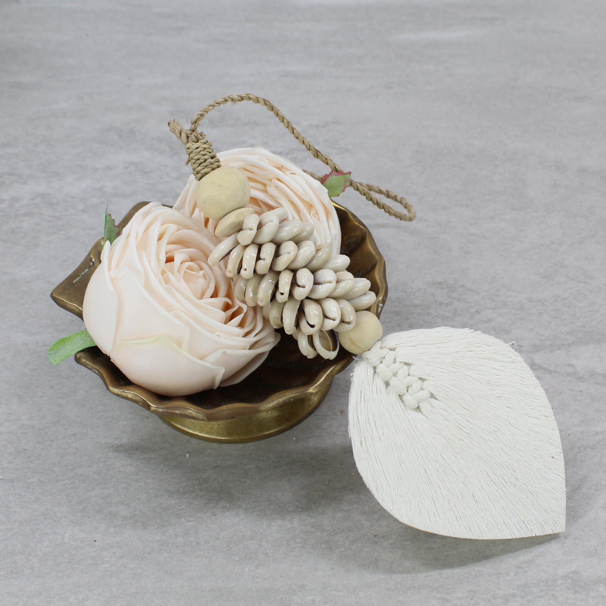 Beige seashell curtain tieback with natural macramé leaf and jute rope displayed beside soft blush rose decor