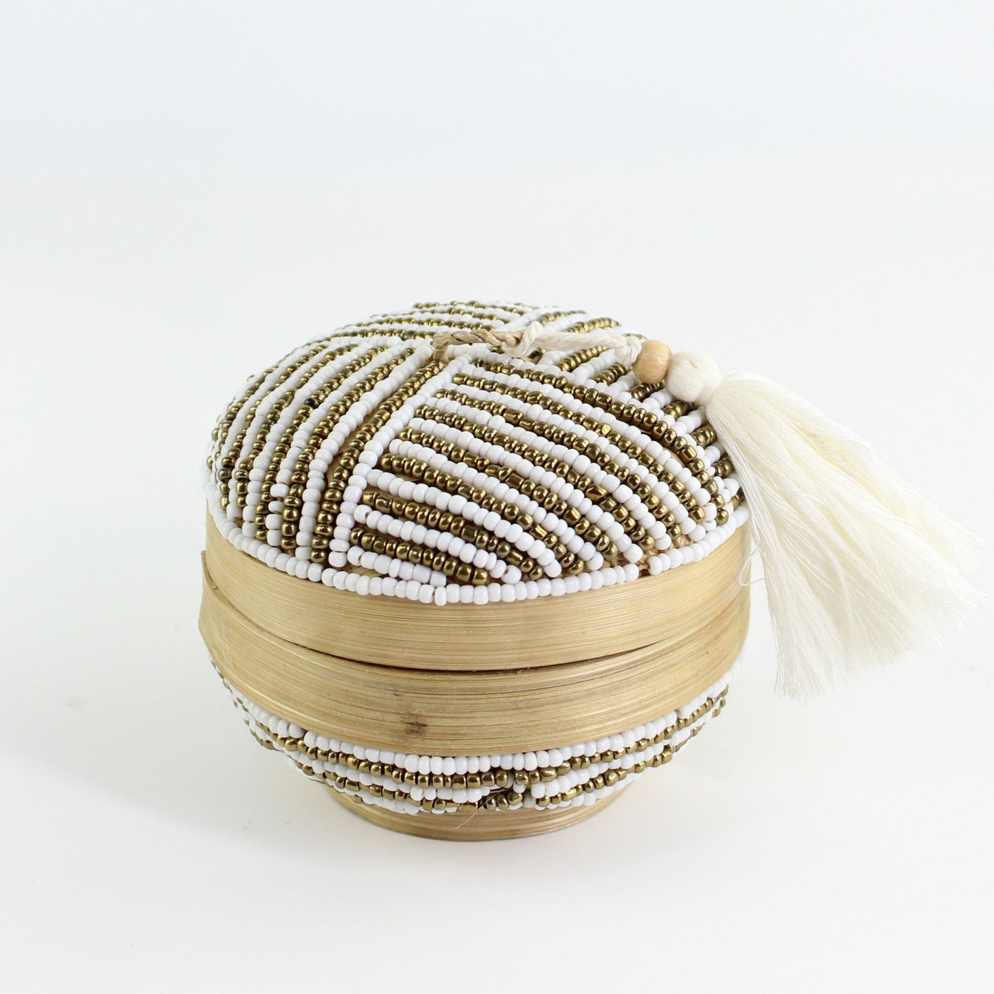 Handmade white and gold linear beaded round bamboo tassel box styled with roses on a gray table