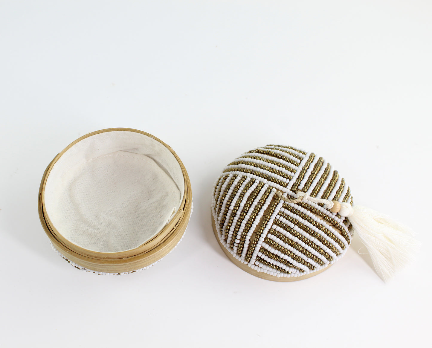 Open handmade white and gold linear beaded bamboo tassel box showing fabric-lined interior