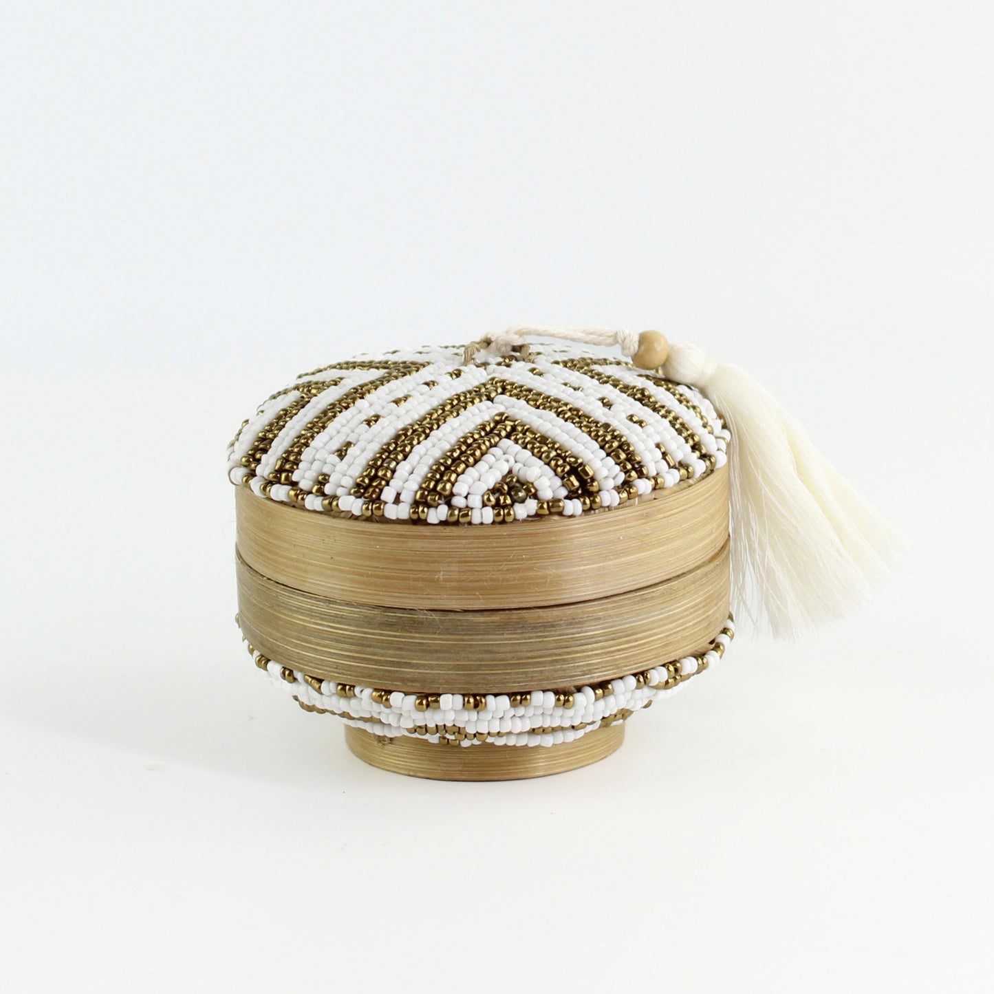 Handcrafted white and gold beaded bamboo jewelry box with ivory tassel, featuring chevron pattern and artisan texture.