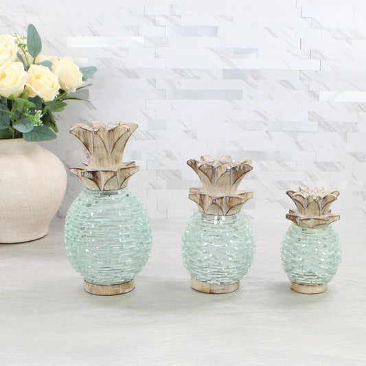 Eco Handcraft handmade pineapple tea light holders in three sizes, crafted with whitewashed wood tops and textured glass bodies, styled on a modern neutral surface with cream roses.