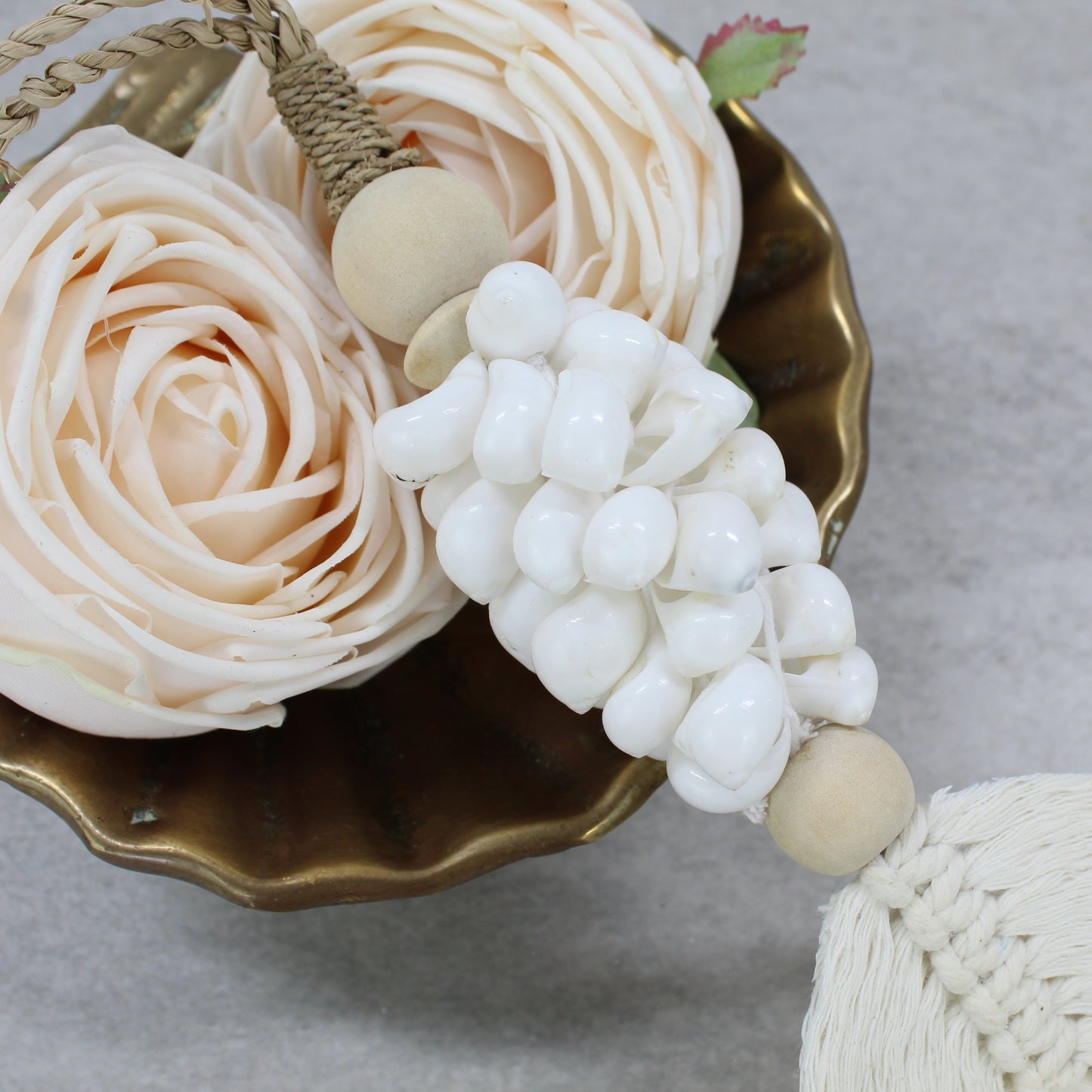 Close-up of white shell tassel handmade with natural jute rope, wood beads, and cotton fringe leaf detail
