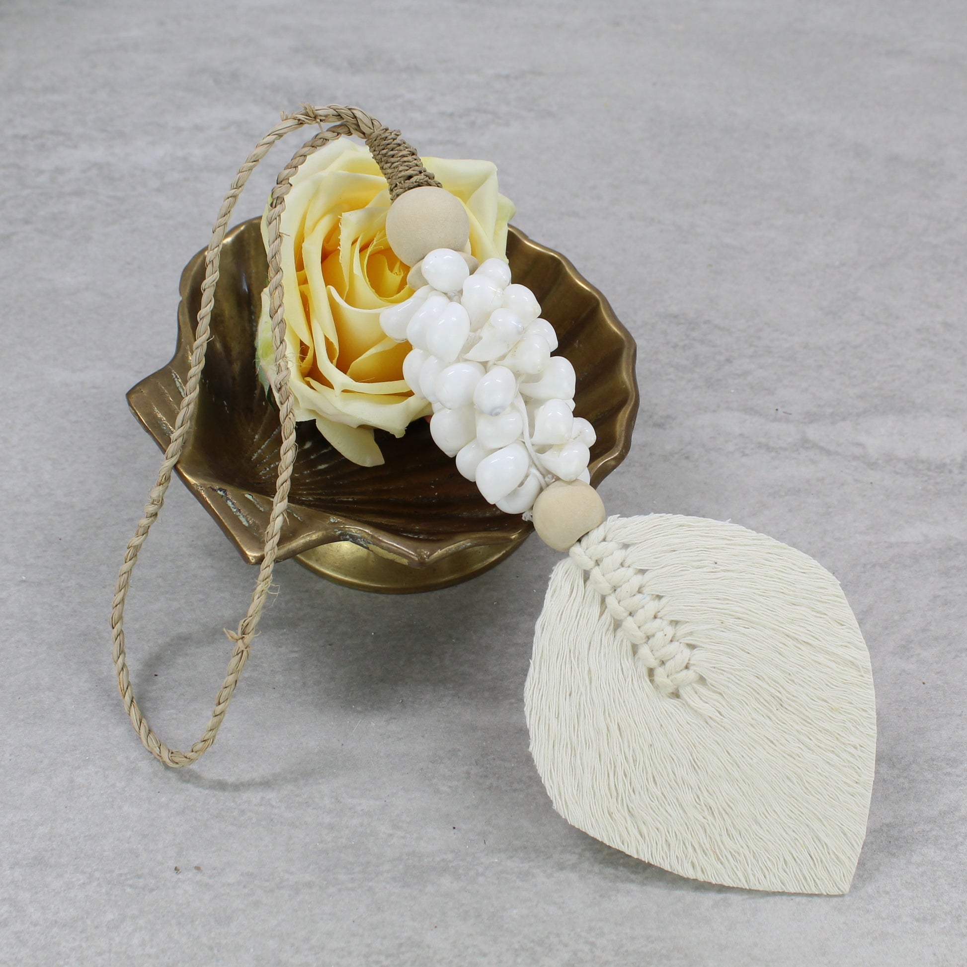 Handmade white shell tassel with macramé cotton leaf and jute hanger styled with yellow rose in bowl decor setup