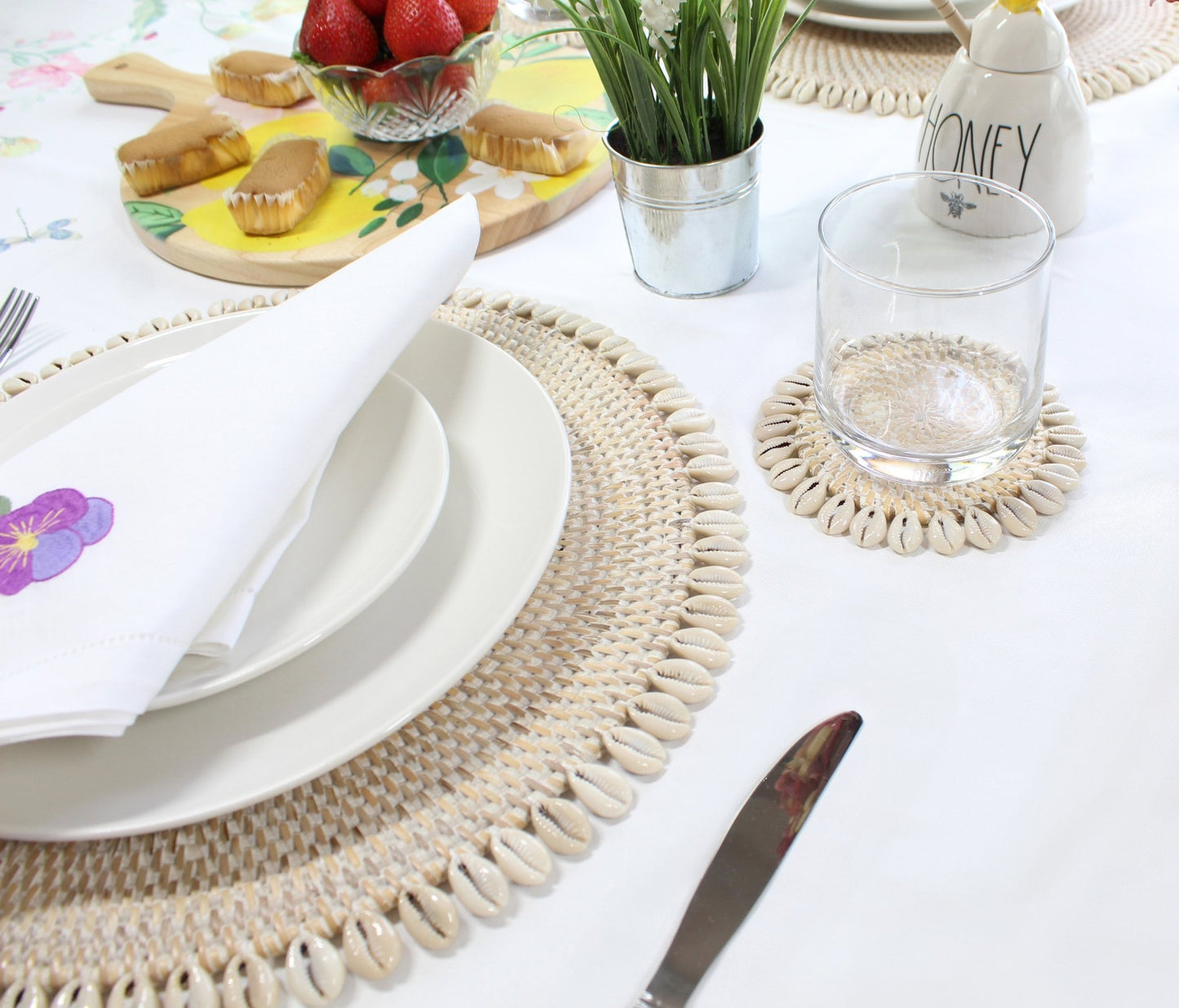 Whitewash eco-friendly rattan coasters styled in coastal home with candles, flowers, and tropical table décor