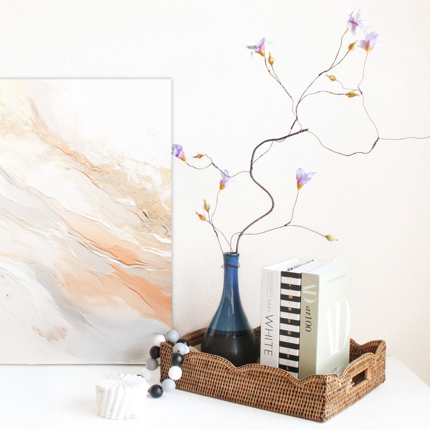 Handmade scalloped rattan tray in honey brown on dresser with blue vase and design books, sustainable woven tray for modern organizing.