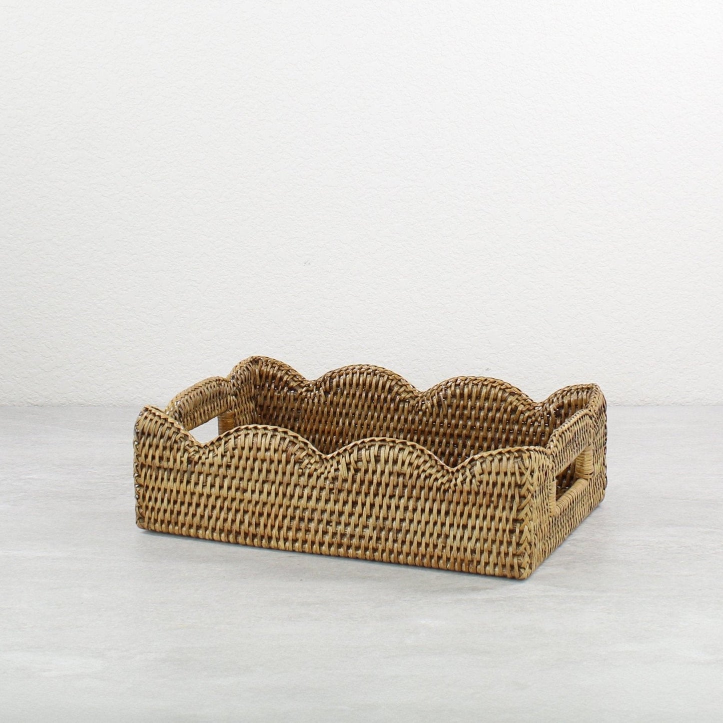 Side angled view of scalloped rectangle rattan tray in honey brown, tight handwoven Burmese rattan basket for serving or organizing.