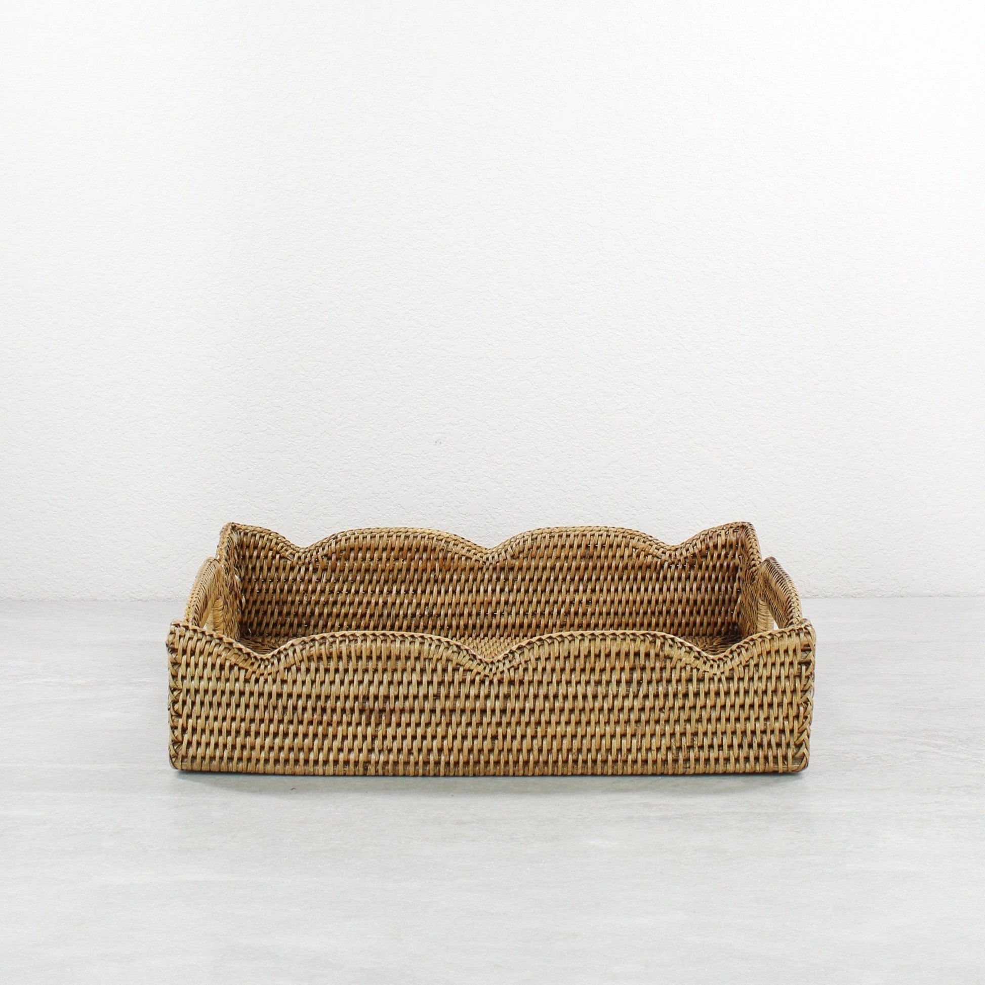 Front view of handmade scalloped rattan tray in honey brown, rectangular storage and serving basket crafted from sustainable Burmese rattan.
