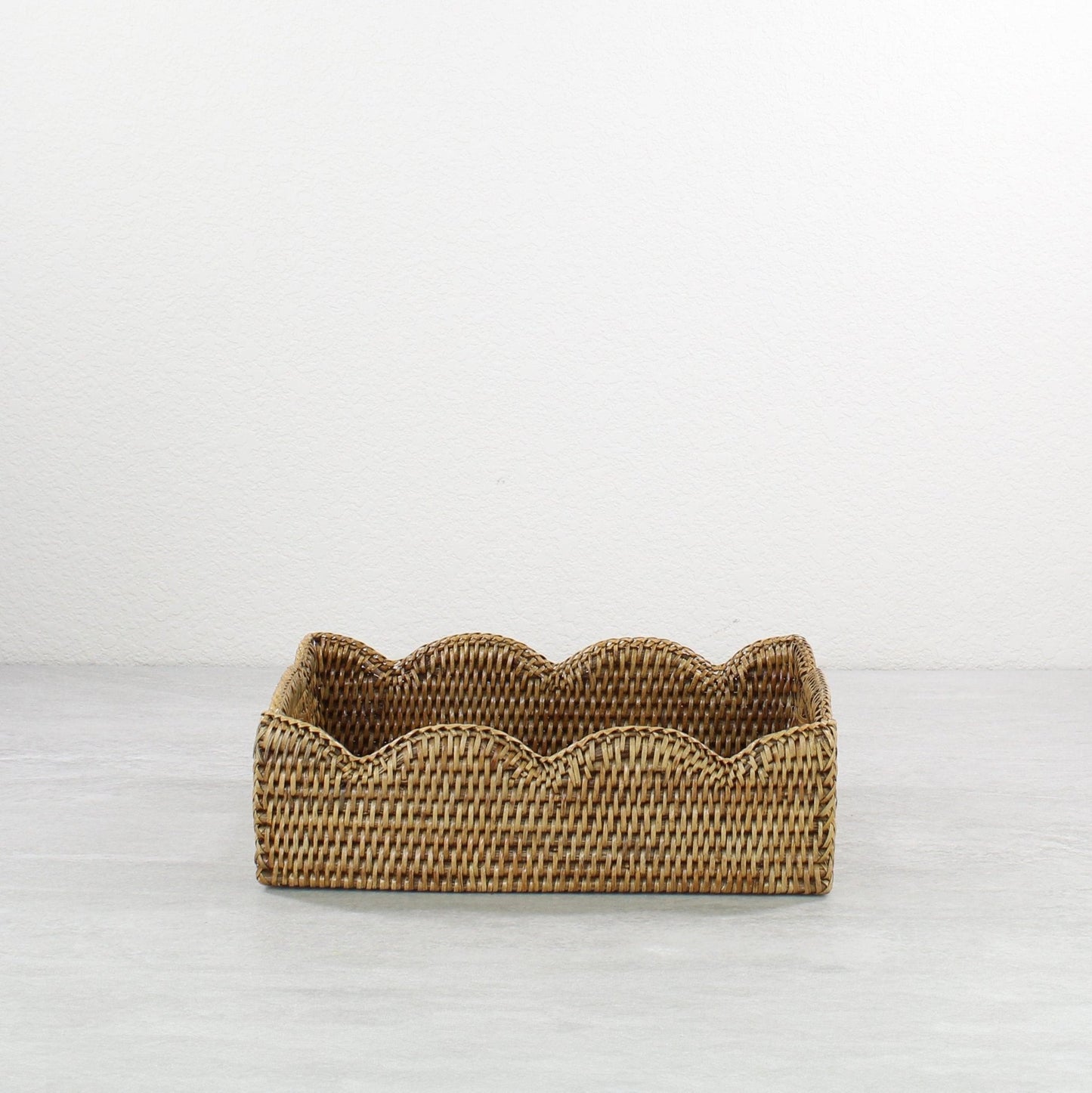 Front view of scalloped edge rattan tray in honey brown, rectangular eco-friendly handmade tray with wavy decorative border.