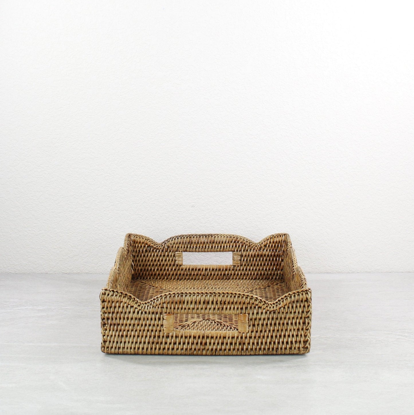 Scalloped rectangle rattan tray in honey brown with built-in side handles, handmade from durable natural rattan for easy carrying and serving.