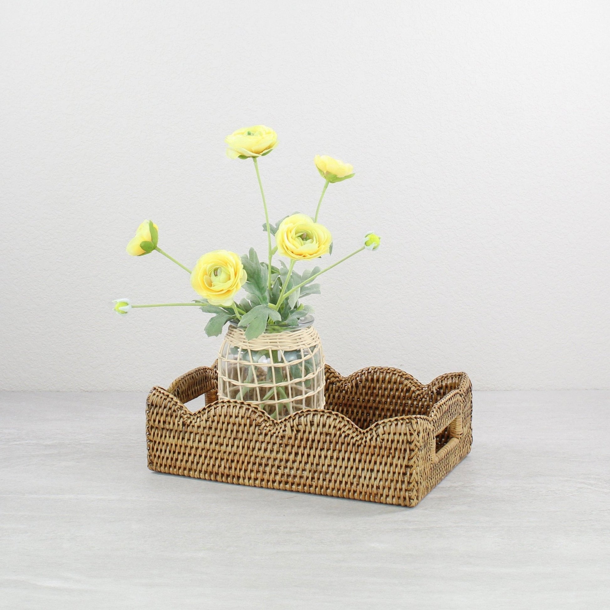Decorative scalloped rattan tray in honey brown styled with yellow flower vase, sustainable handmade home décor accent for coffee tables or dining.