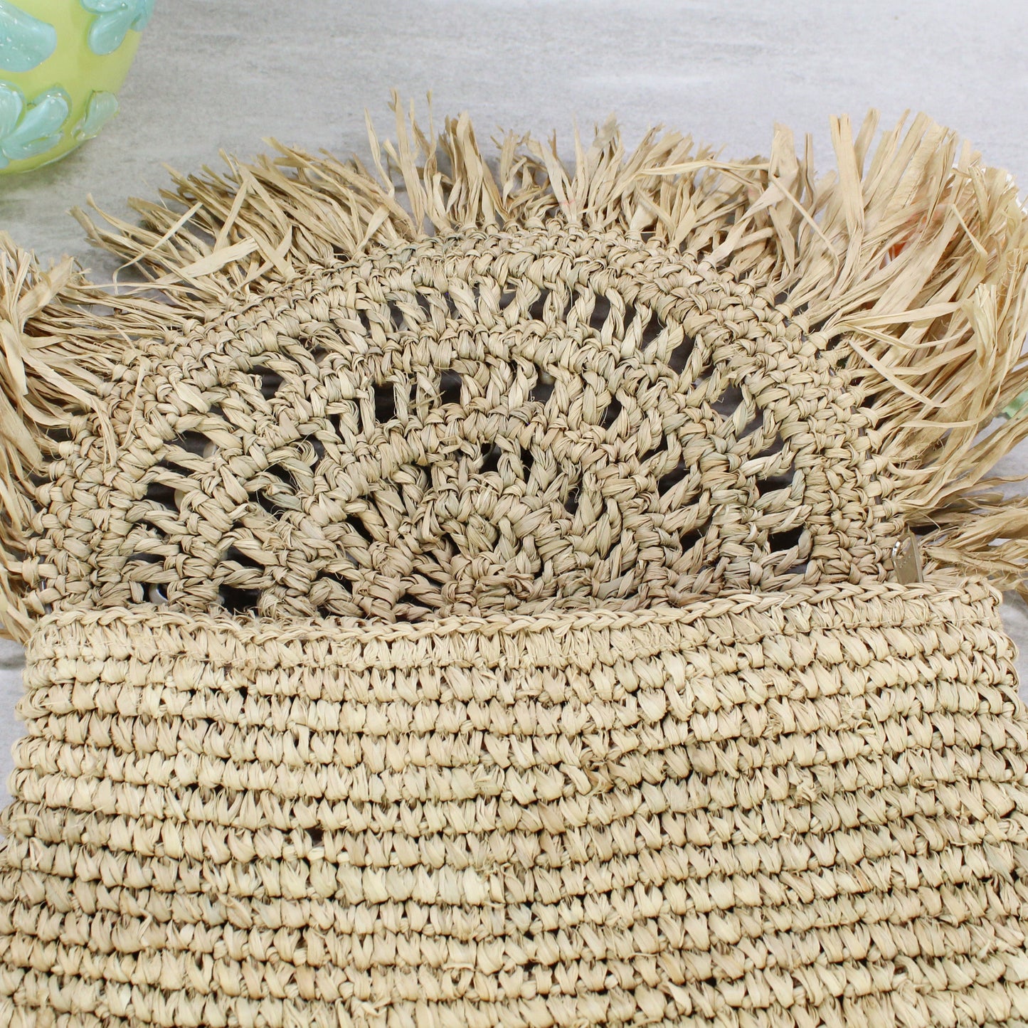 Open view of raffia clutch showing semi-circular woven pattern under flap — eco-friendly handmade design.