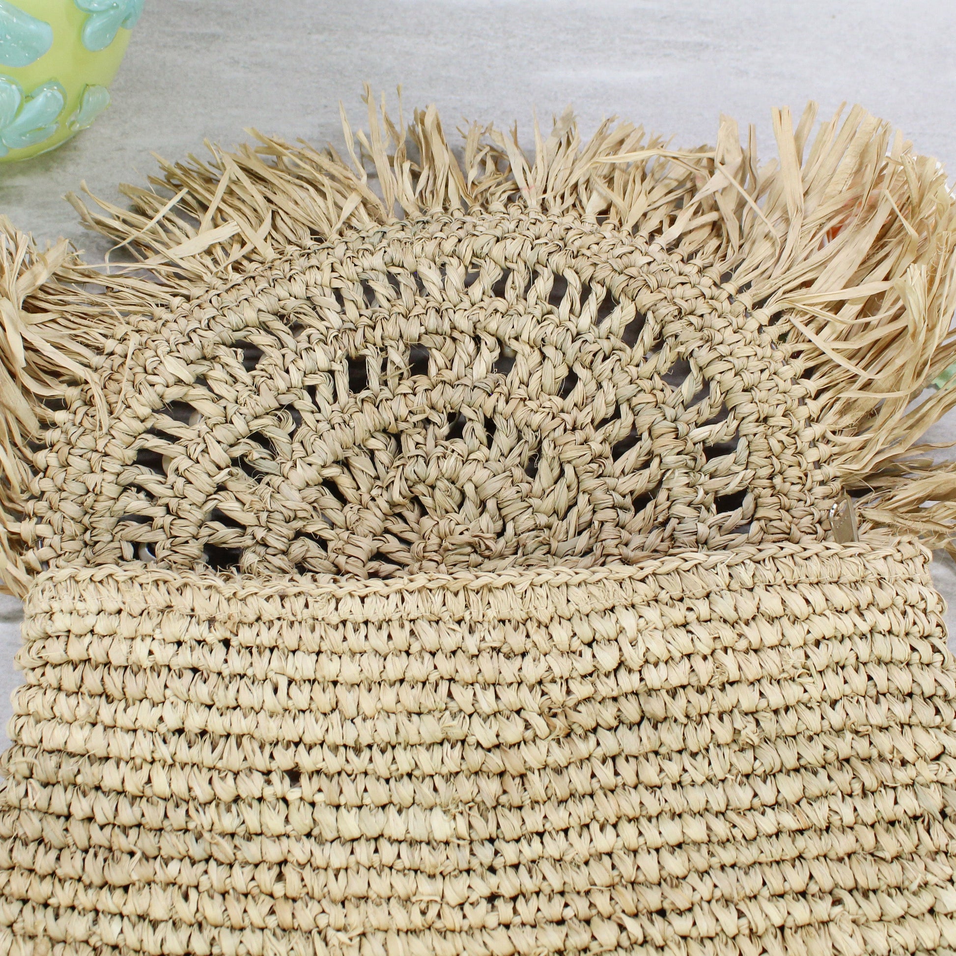 Open view of raffia clutch showing semi-circular woven pattern under flap — eco-friendly handmade design.