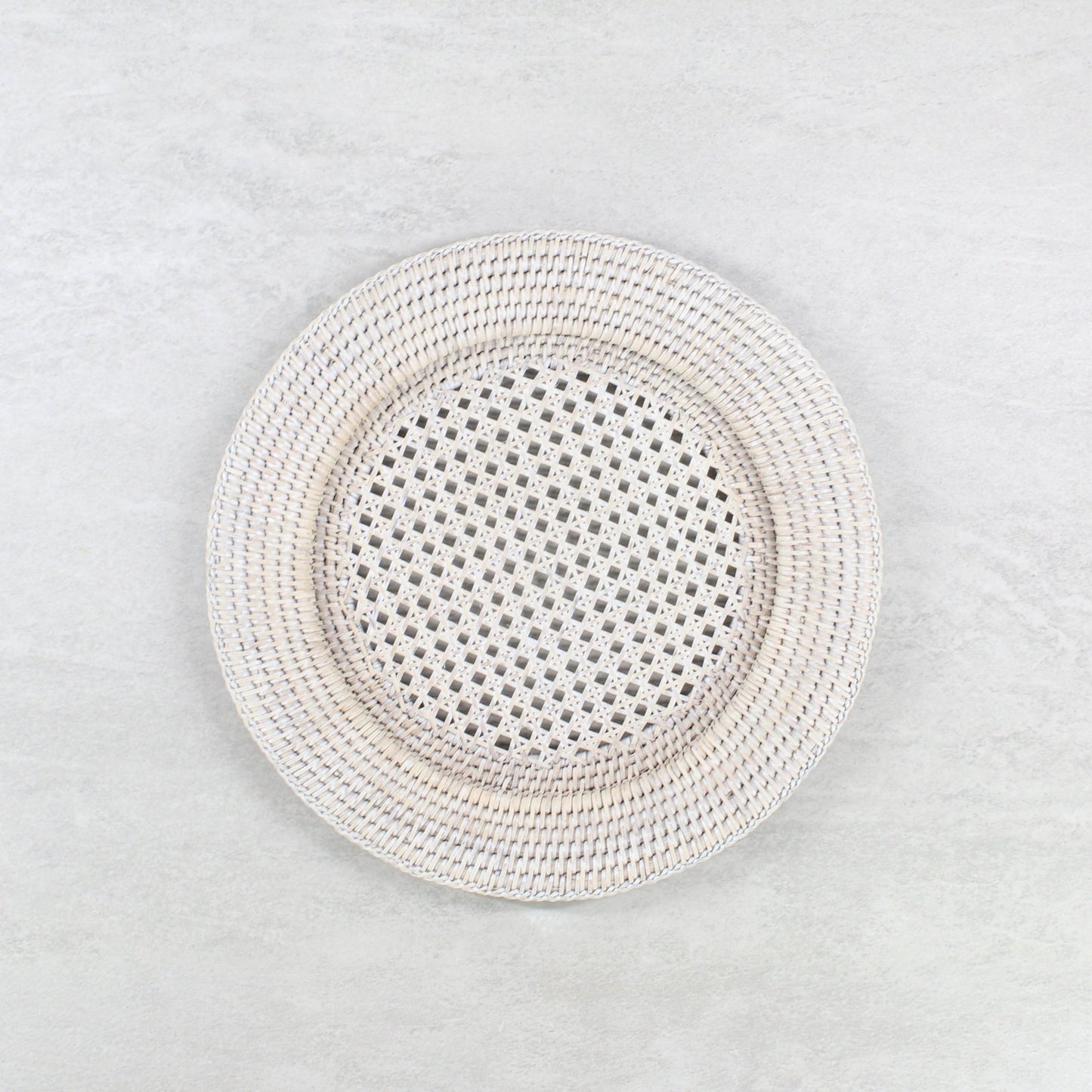 Eco Handcraft handmade whitewash rattan placemat on a light grey table.