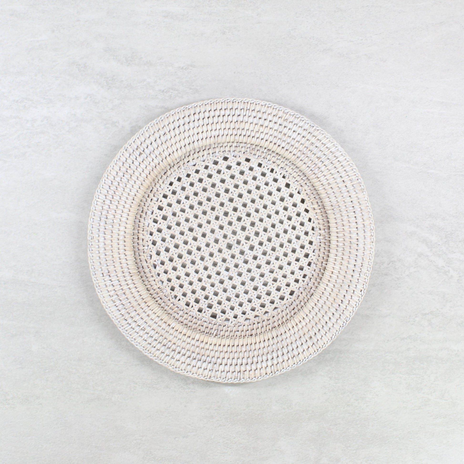 Eco Handcraft handmade whitewash rattan placemat on a light grey table.