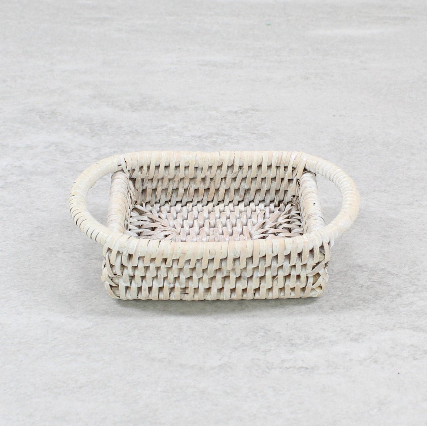 Whitewashed rectangular rattan tray with rounded handles, handwoven for kitchen or bathroom countertop organization.