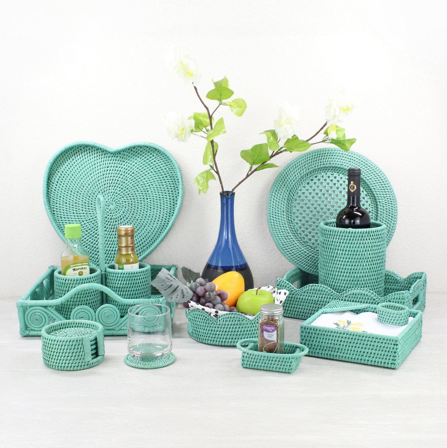 Turquoise rattan dining set with trays, holders, and coasters, styled with fruit and flowers for kitchen or gift use.