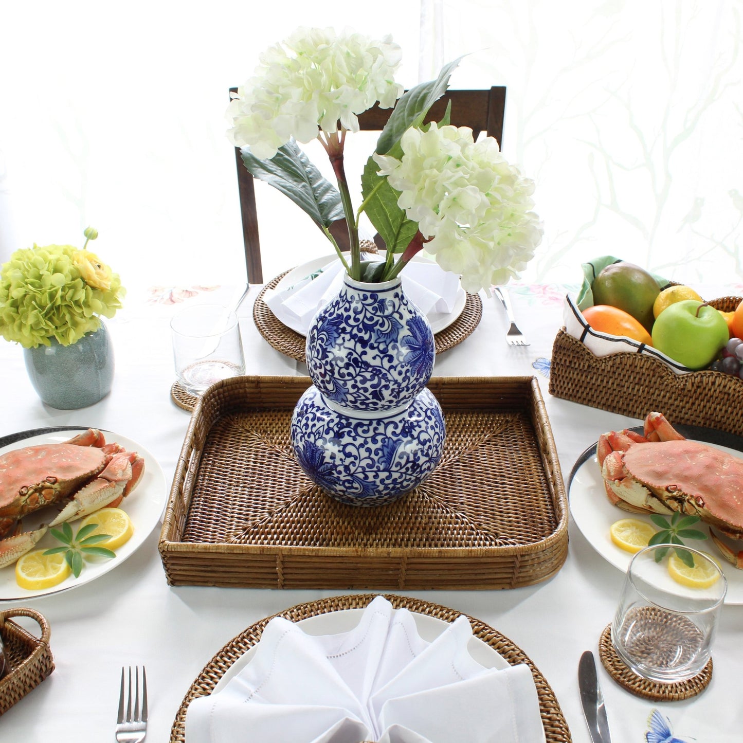 ECO HANDCRAFT leaf shaped rattan tray holding blue ceramic vase with white flowers on a styled dining table
