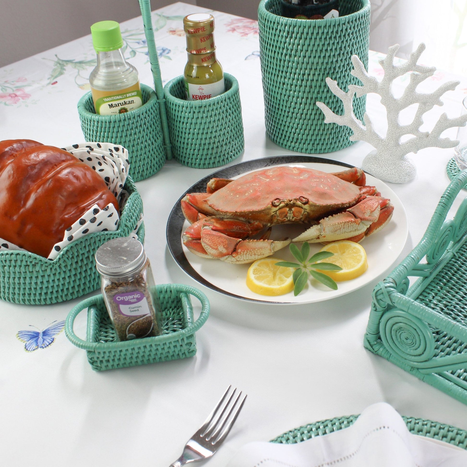 Eco Handcraft turquoise rattan condiment holders and bread basket on coastal dining table with crab dish