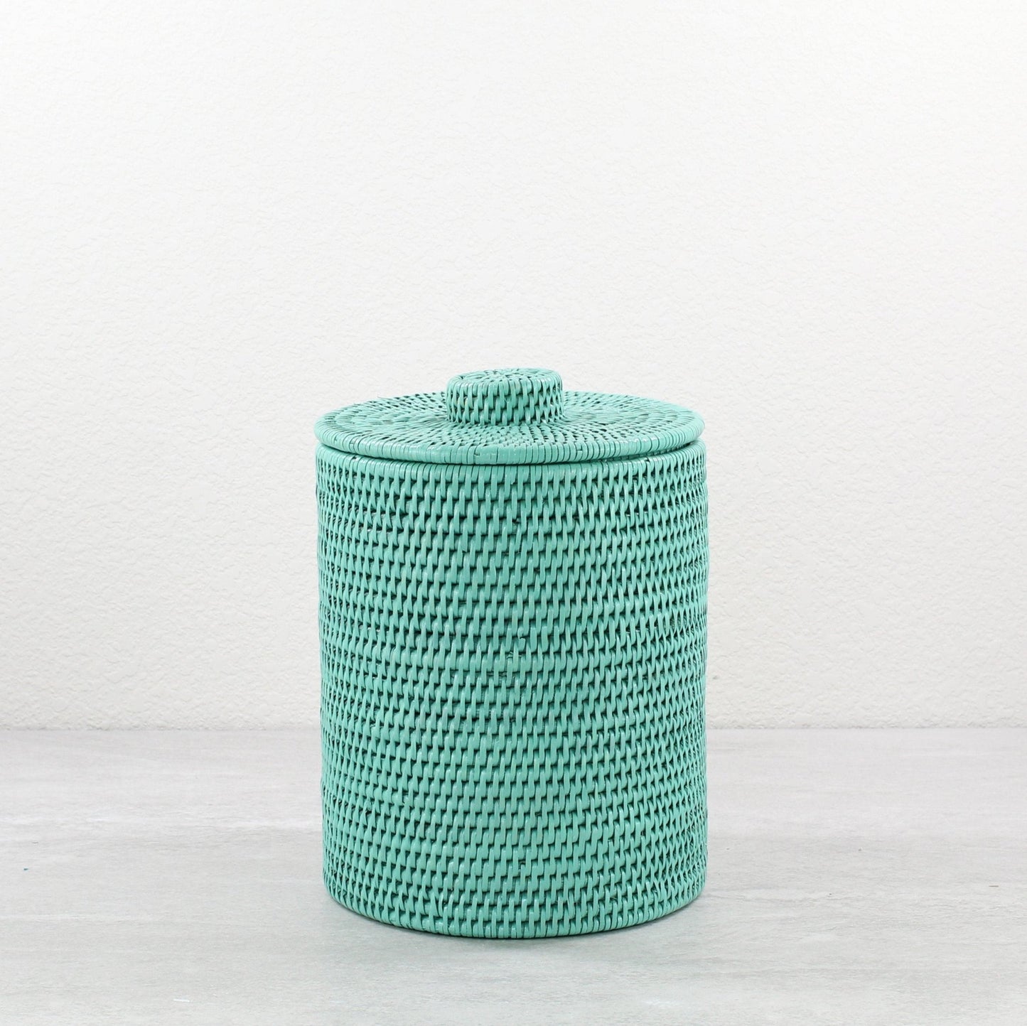 Turquoise round rattan waste bin with lid, tightly woven and handmade, shown on white background for product display.