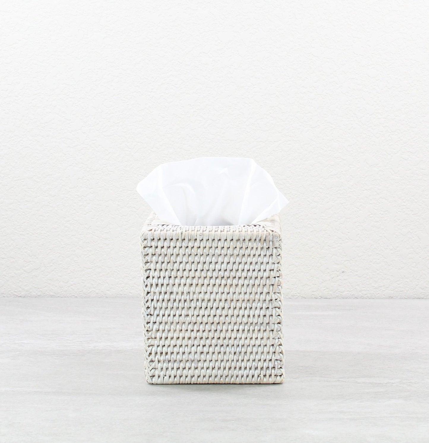 Handwoven whitewash rattan tissue box cover for bathroom or vanity decor, square shape.