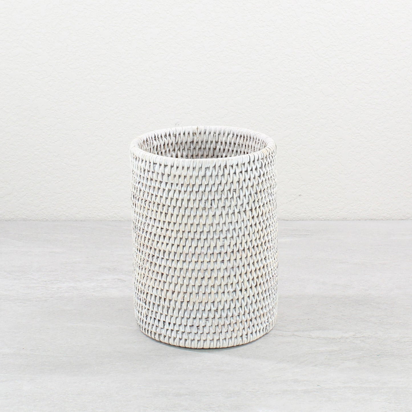 Whitewash rattan wine bottle holder on a light surface.