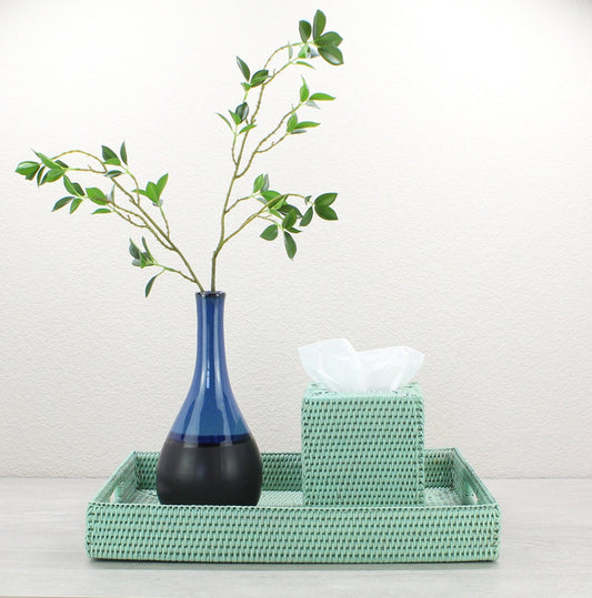 Sage leaf green rectangular rattan tray holding ceramic vase with branch, styled on console for fresh modern look.