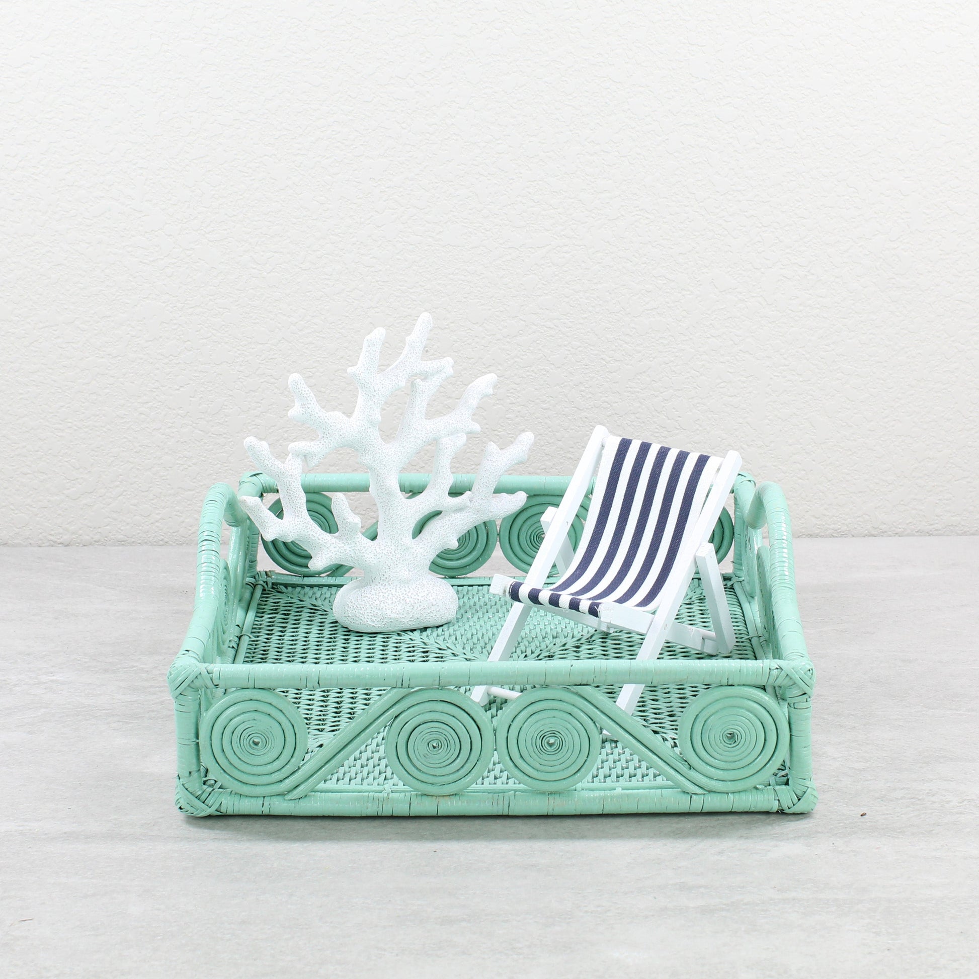 Sage Leaf Green rattan tray styled with white coral sculpture and striped miniature deck chair for coastal-inspired home décor.