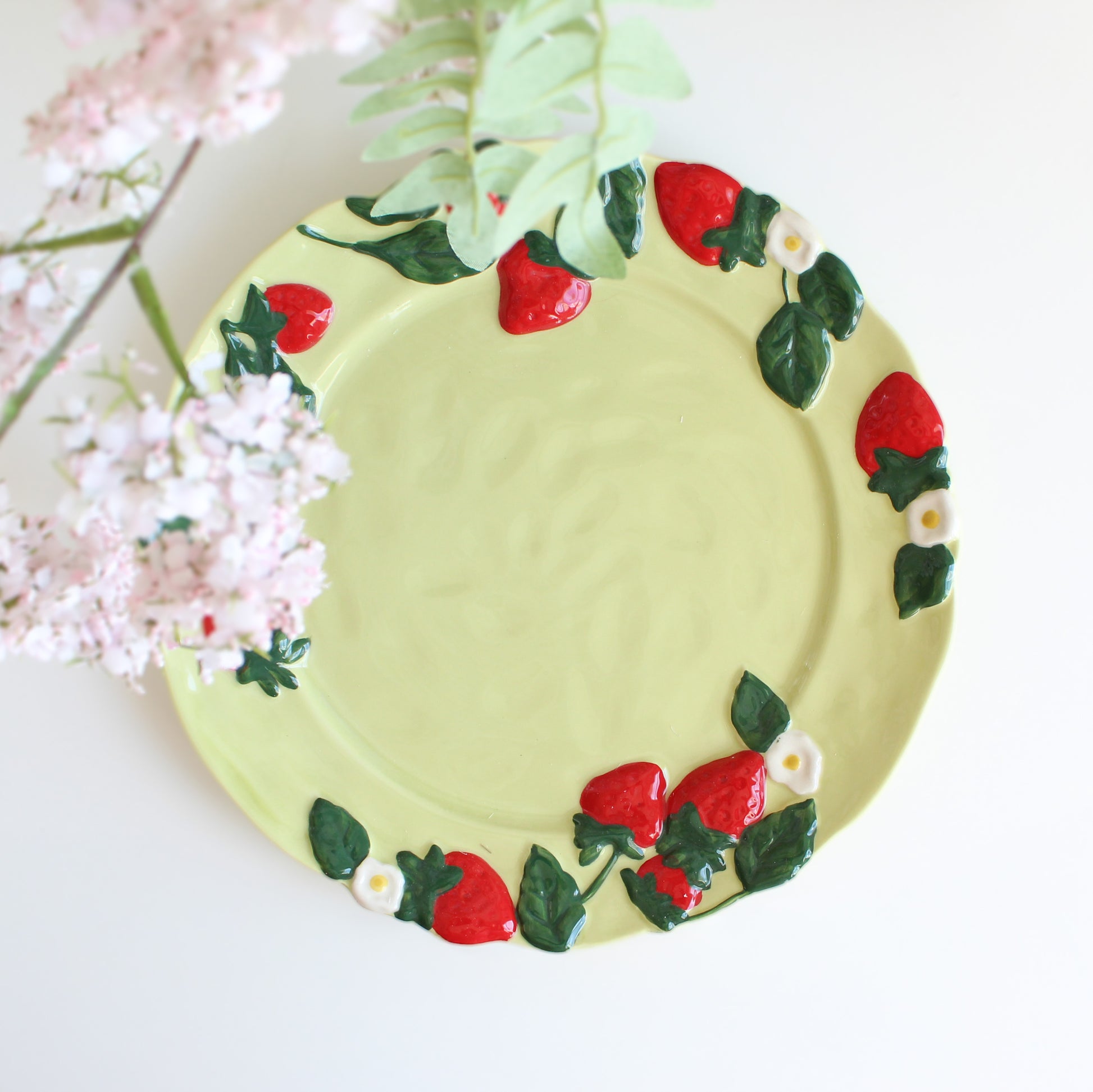 Close-up of strawberry embossed handpainted stoneware dessert plate, green ceramic dish