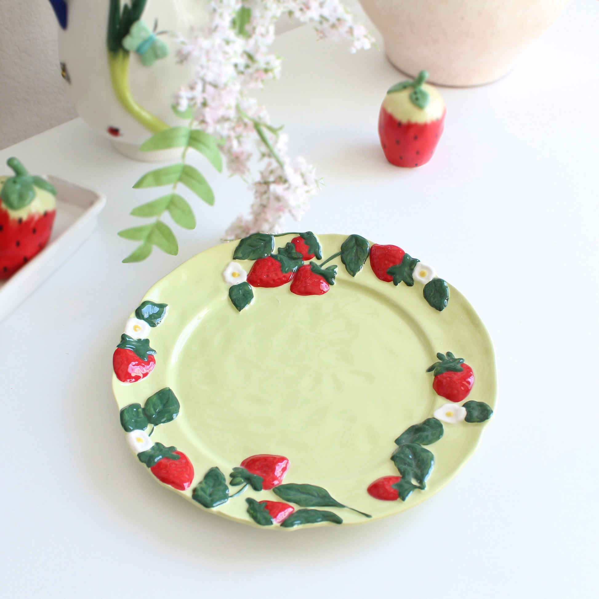 Detailed view of strawberry and floral embossed rim on handpainted stoneware dessert plate