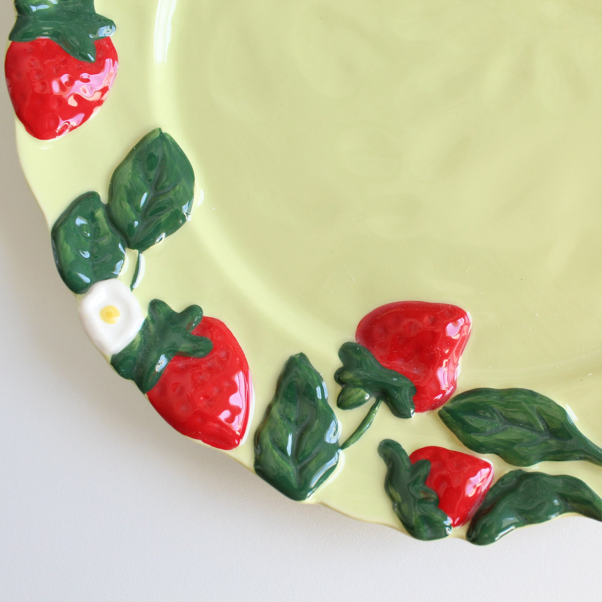 Close-up of strawberry embossed handpainted stoneware dessert plate, green ceramic dish